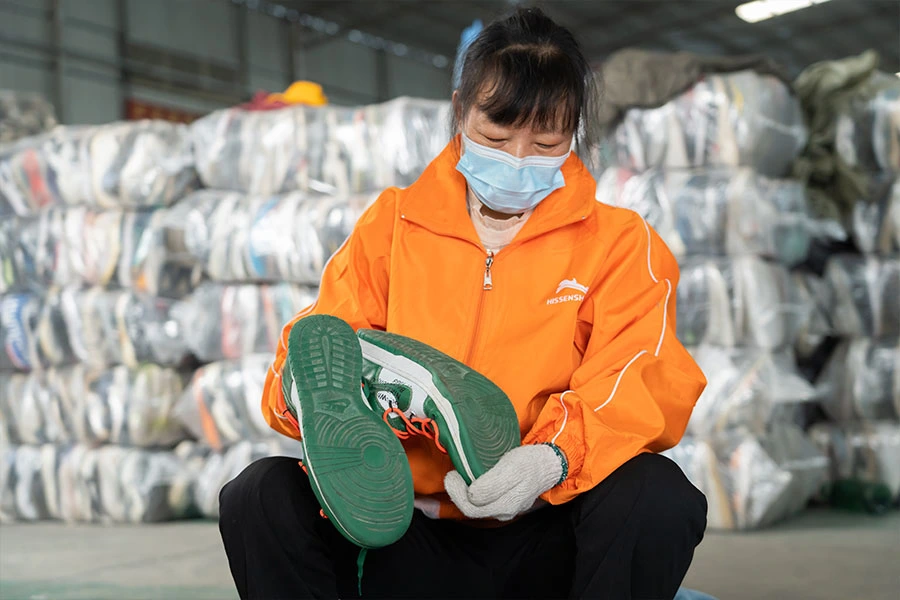 expert sorter checking the quality of a used vintage shoe sole as part of the inspection process.