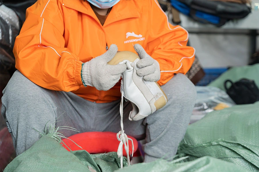 Sorter checking the quality of the used vintage shoes' soles