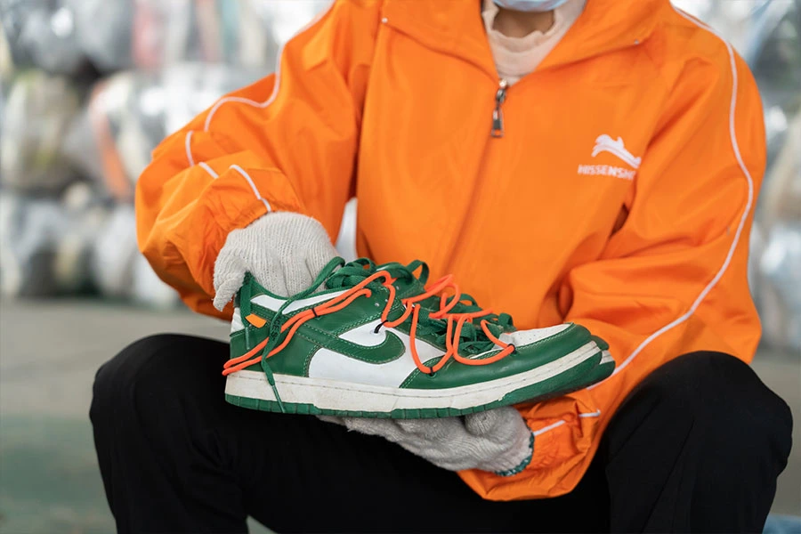 Sorter checking the quality of a used vintage branded shoes.