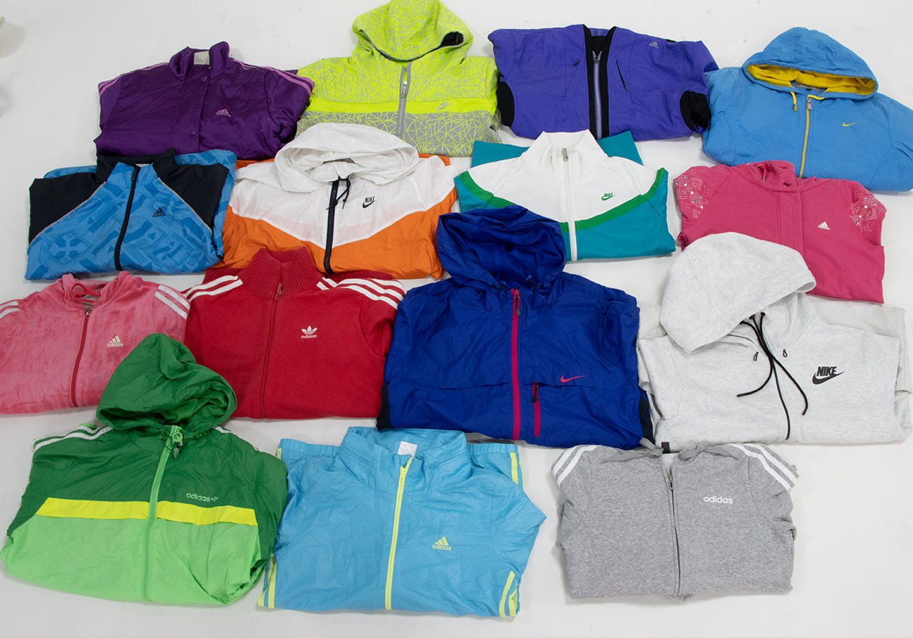 A collection of used vintage branded hoodies neatly folded and arranged into rows.