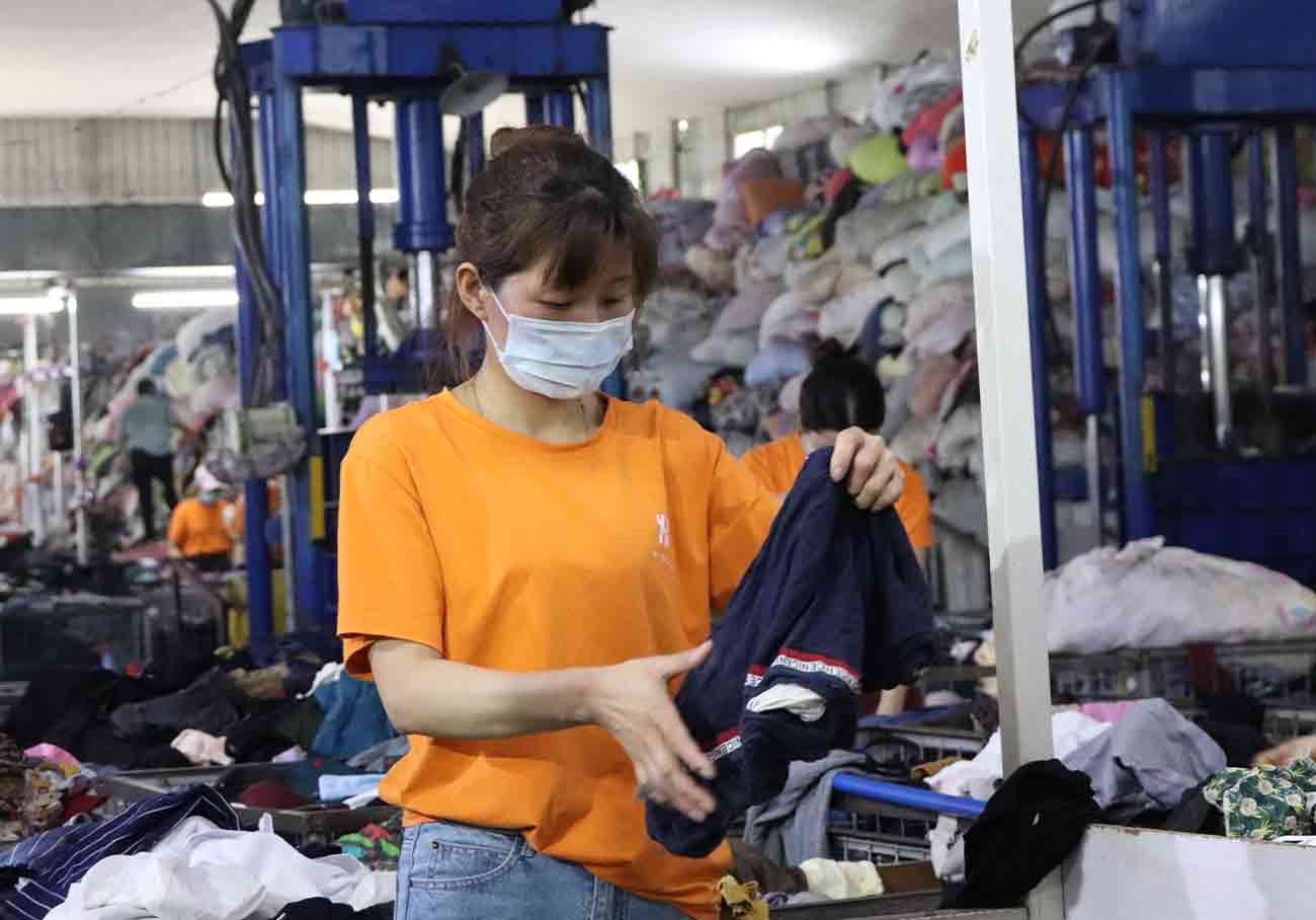 An expert sorter going thorough an order of used vintage clothing wholesale as part of the order fulfillment process.