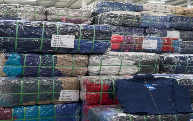 Compressed bales of polar fleece jackets and pullovers at a clothing warehouse, bulk winter outerwear stacked for export